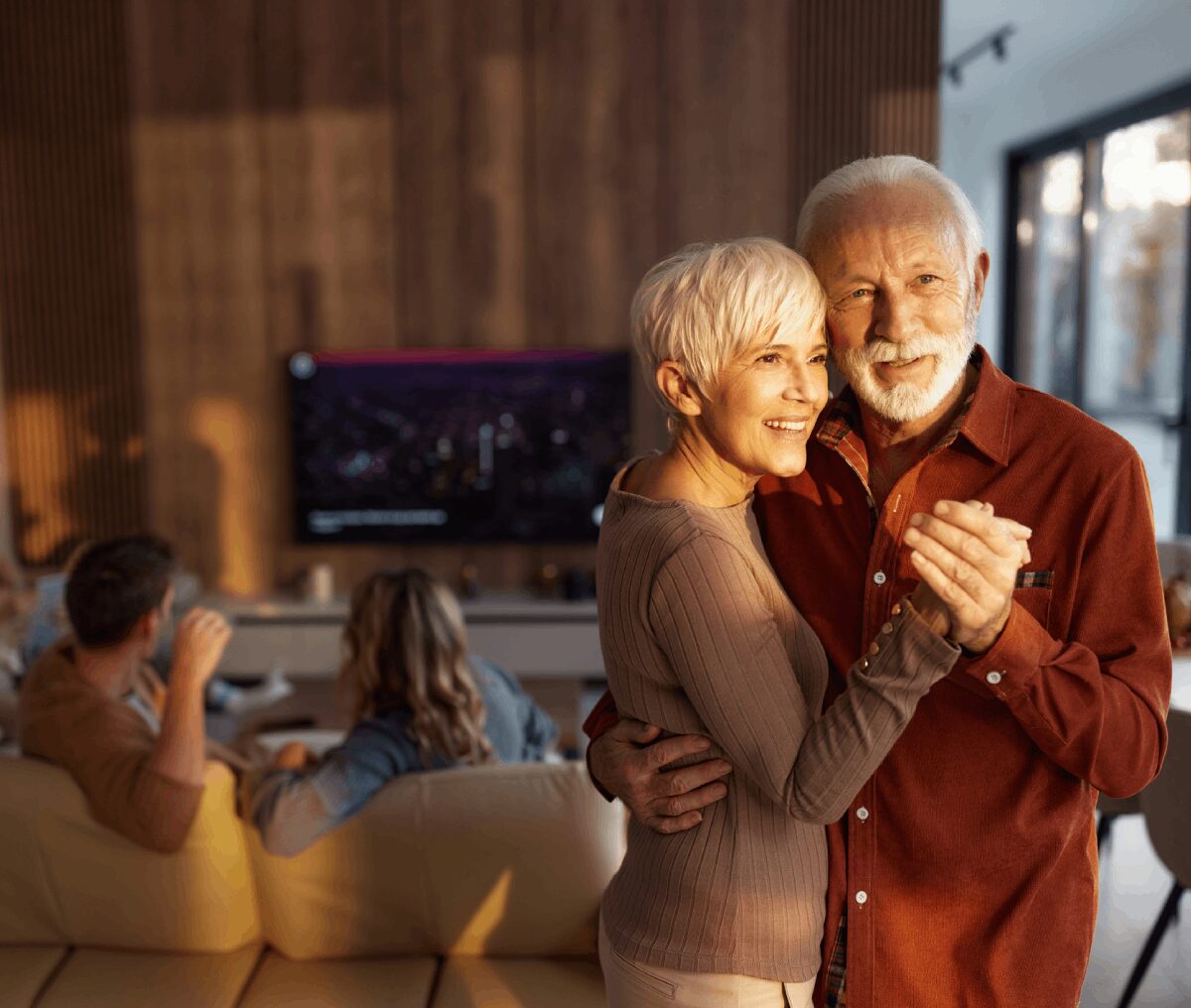 Elderly couple dancing in a cozy living room.