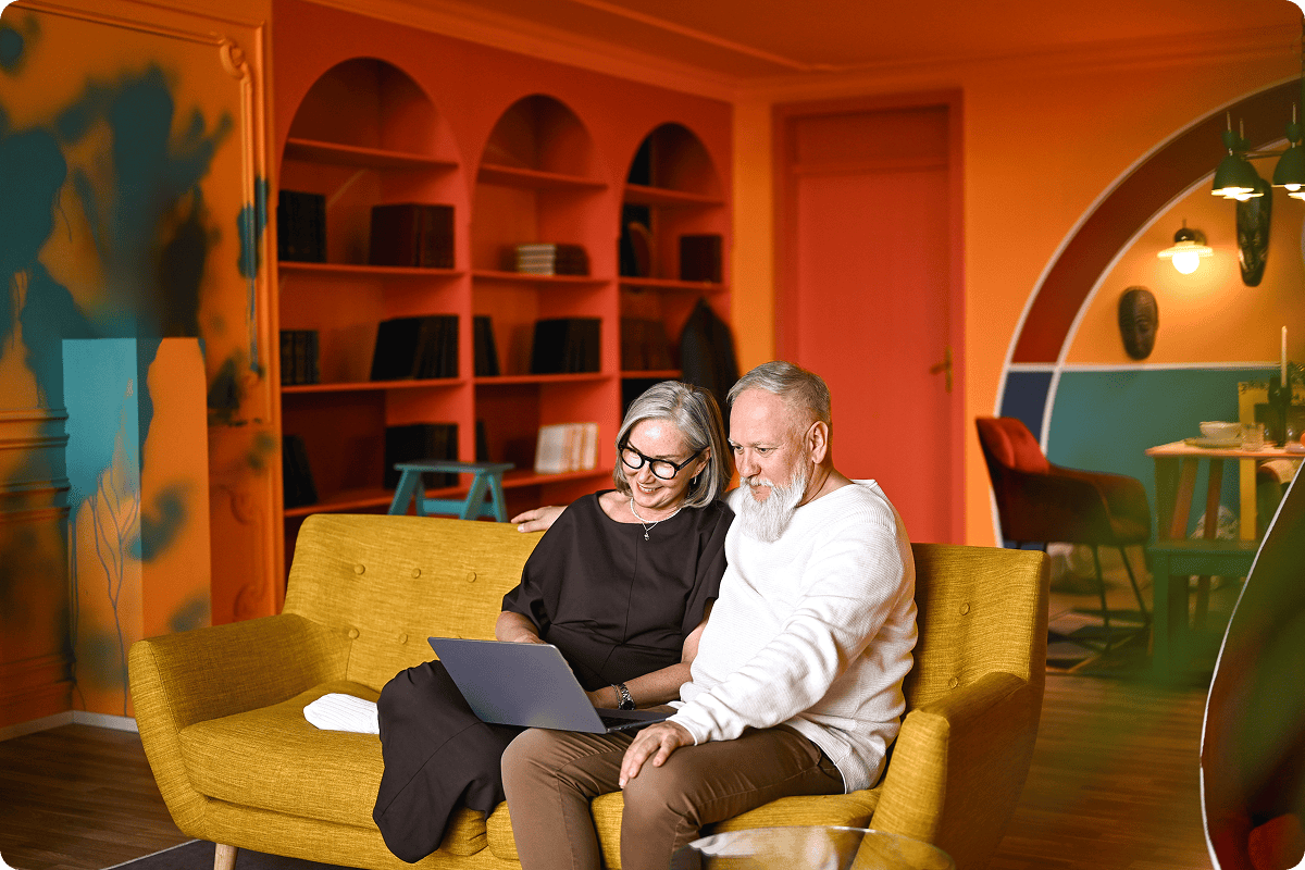 Elderly couple smiling at laptop together.
