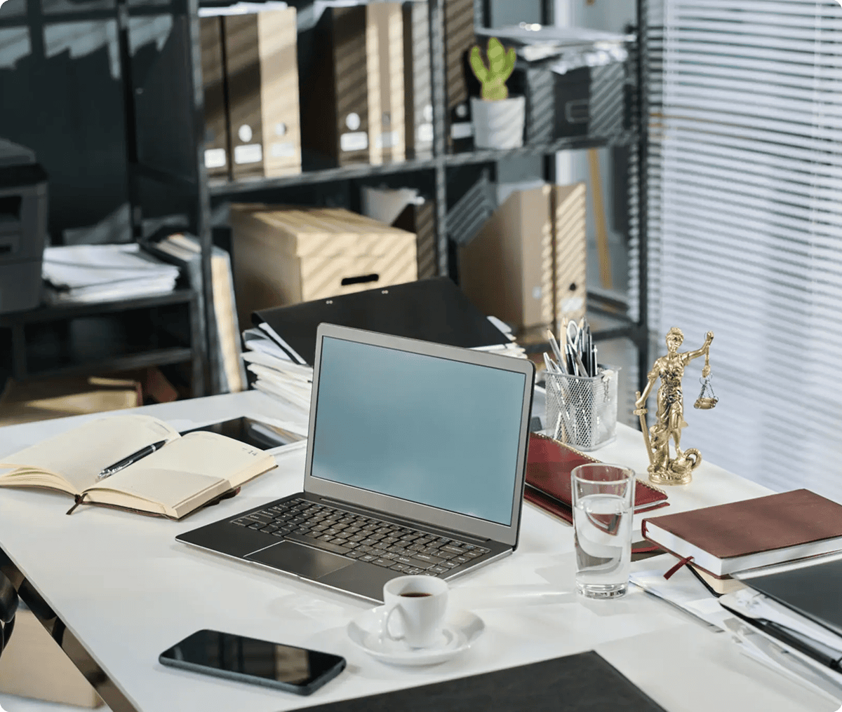 Office desk with laptop and legal statue.