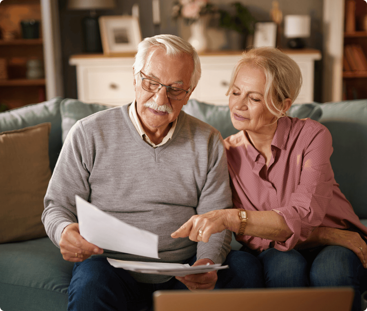 Elderly couple reviewing documents on couch.